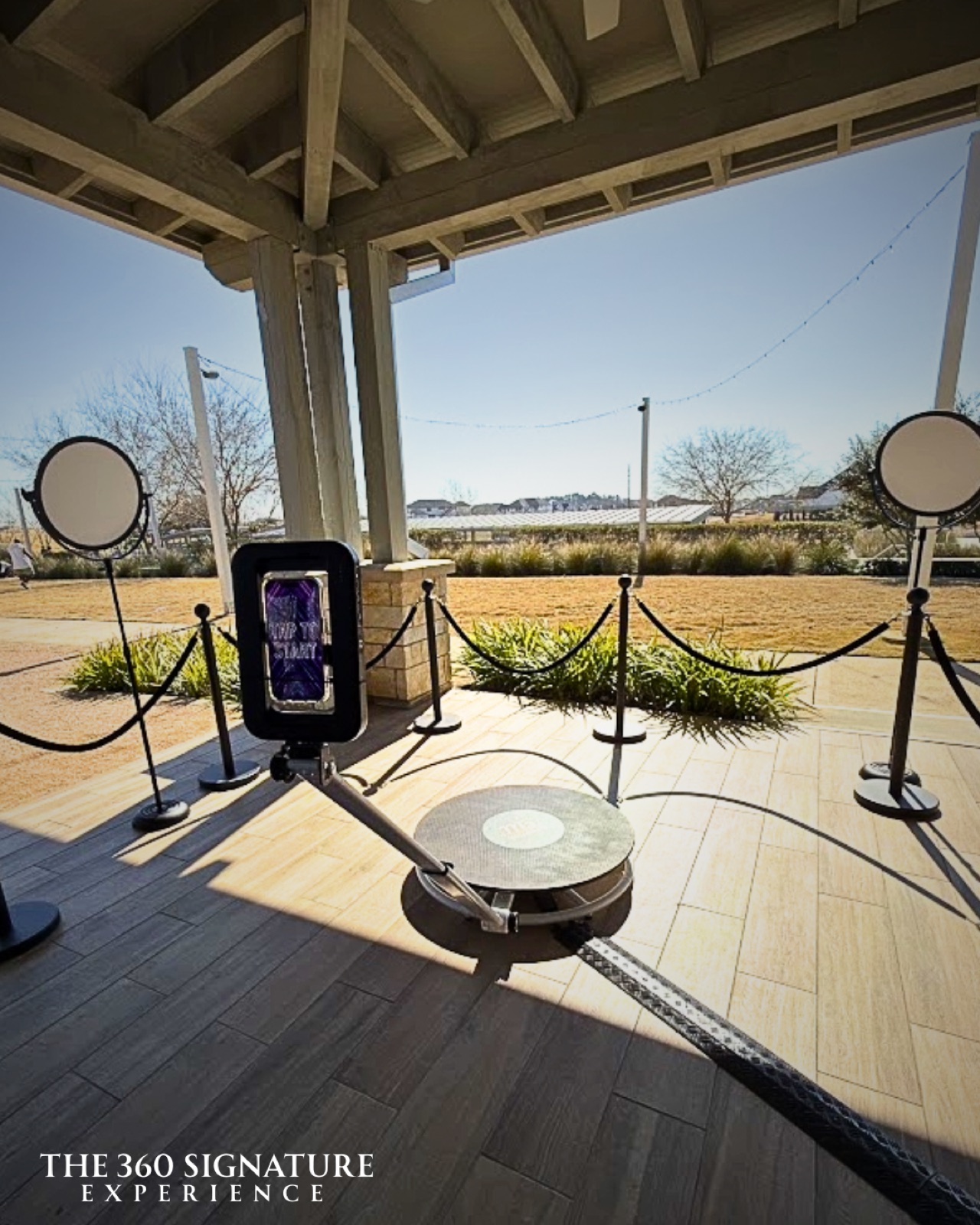 The spinning video platform under a covered patio, roped off with stanchions, open country visible beyond