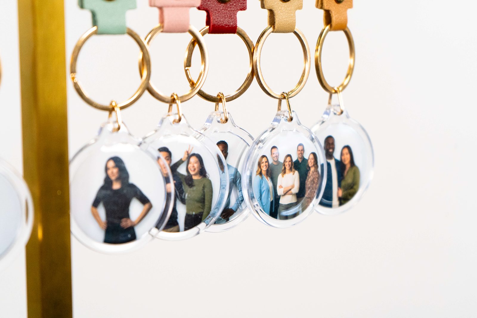 A row of clear round keychains on gold rings, each one holding a photo of a different group of guests